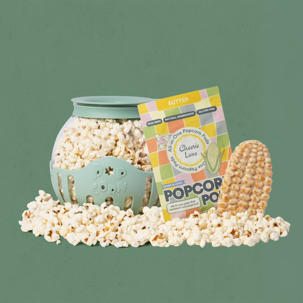 Popcorn popper with popcorn kernels, a bag of popcorn, and a popcorn kernel on a green background