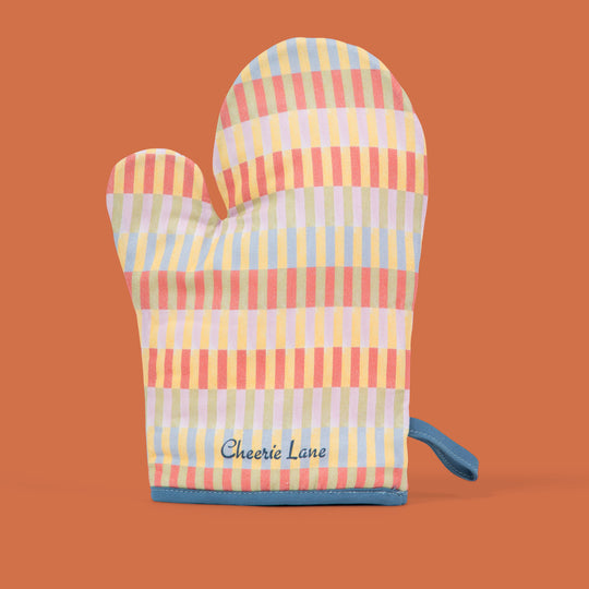 Colorful striped oven mitt and pot holder set on an orange background