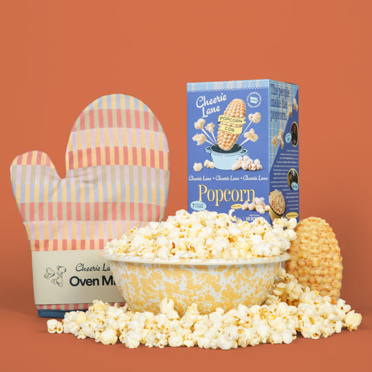 Popcorn with a box of Cheerie Lane Popcorn and an oven mitt on a brown background