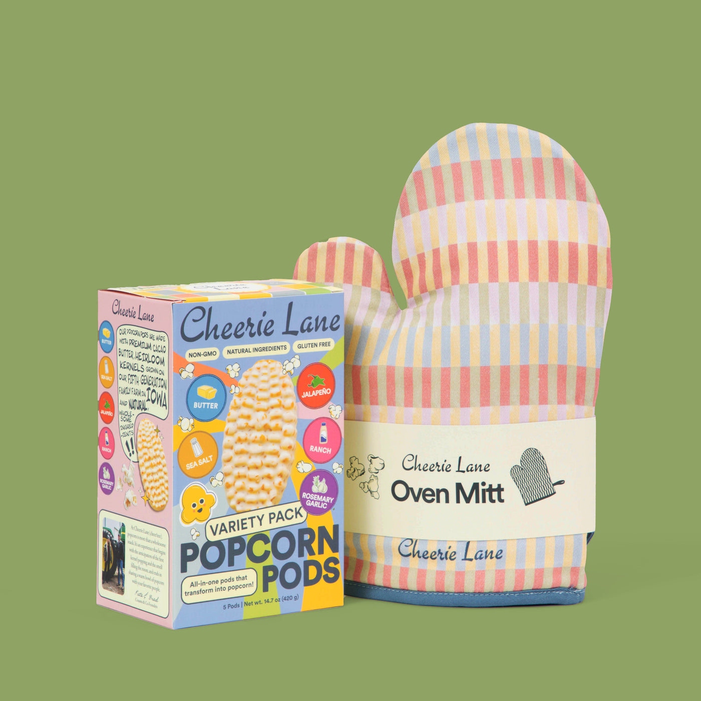 Colorful oven mitt and popcorn pods packaging on a green background