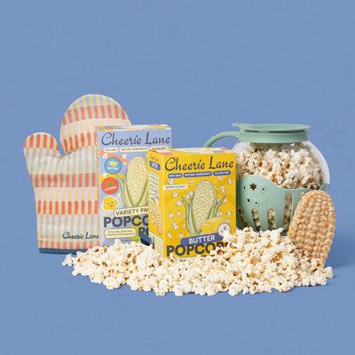 Popcorn-making kit with Cheerie Lane popcorn and accessories on a blue background
